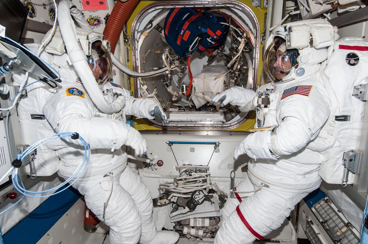 ISS038-E-019271 (20 Dec. 2013) --- In the Quest airlock onboard the Earth-orbiting International Space Station, on the eve of their first spacewalk together,  NASA astronauts Rick Mastracchio, right, and Mike Hopkins are completely suited in their extravehicular mobility unit spacesuits.  NASA has scheduled at least two sessions of extravehicular activity for the two flight engineers to troubleshoot a faulty coolant pump on the orbital outpost.