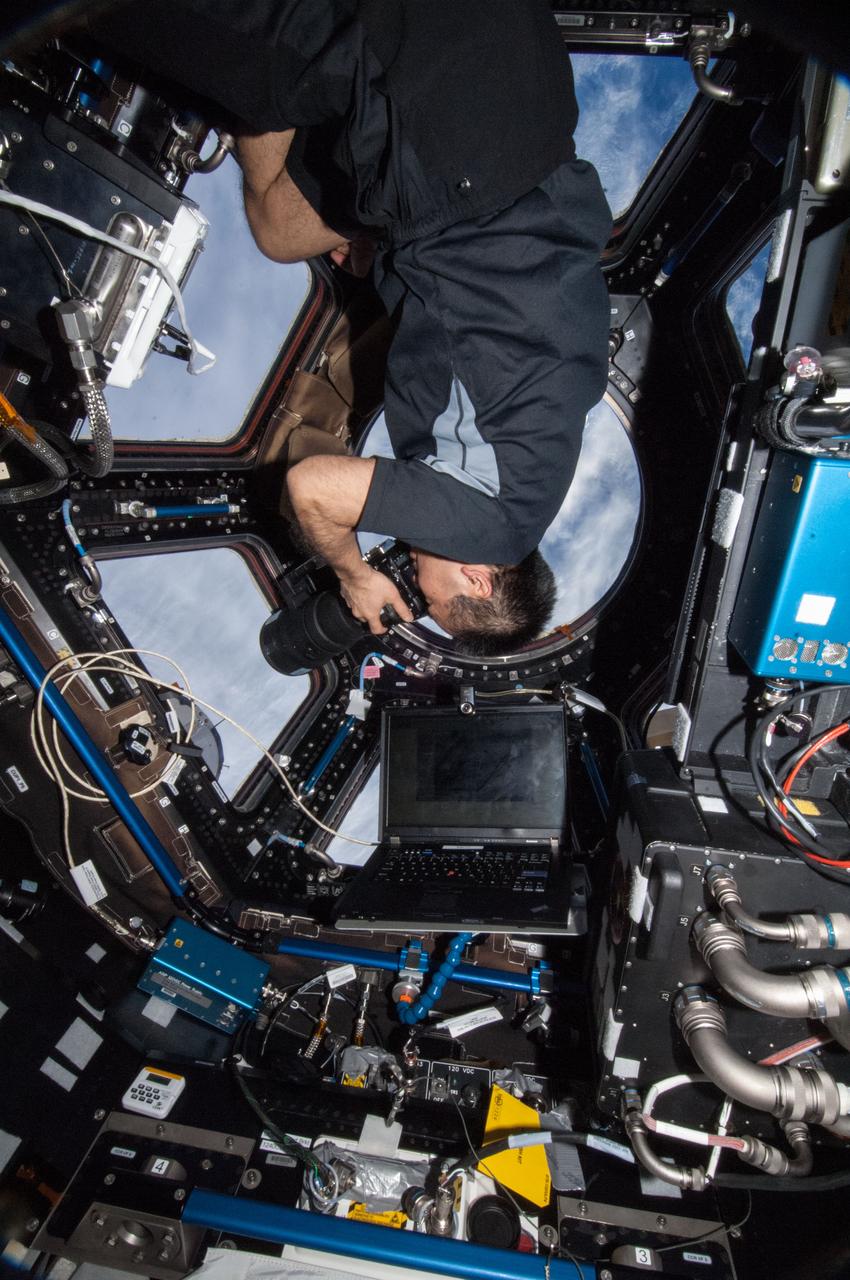 ISS038-E-021630 (28 Dec. 2013) --- Japan Aerospace Exploration Agency astronaut Koichi Wakata, Expedition 38 flight engineer, uses a still camera to photograph the topography of a point on Earth from a window in the Cupola of the International Space Station.
