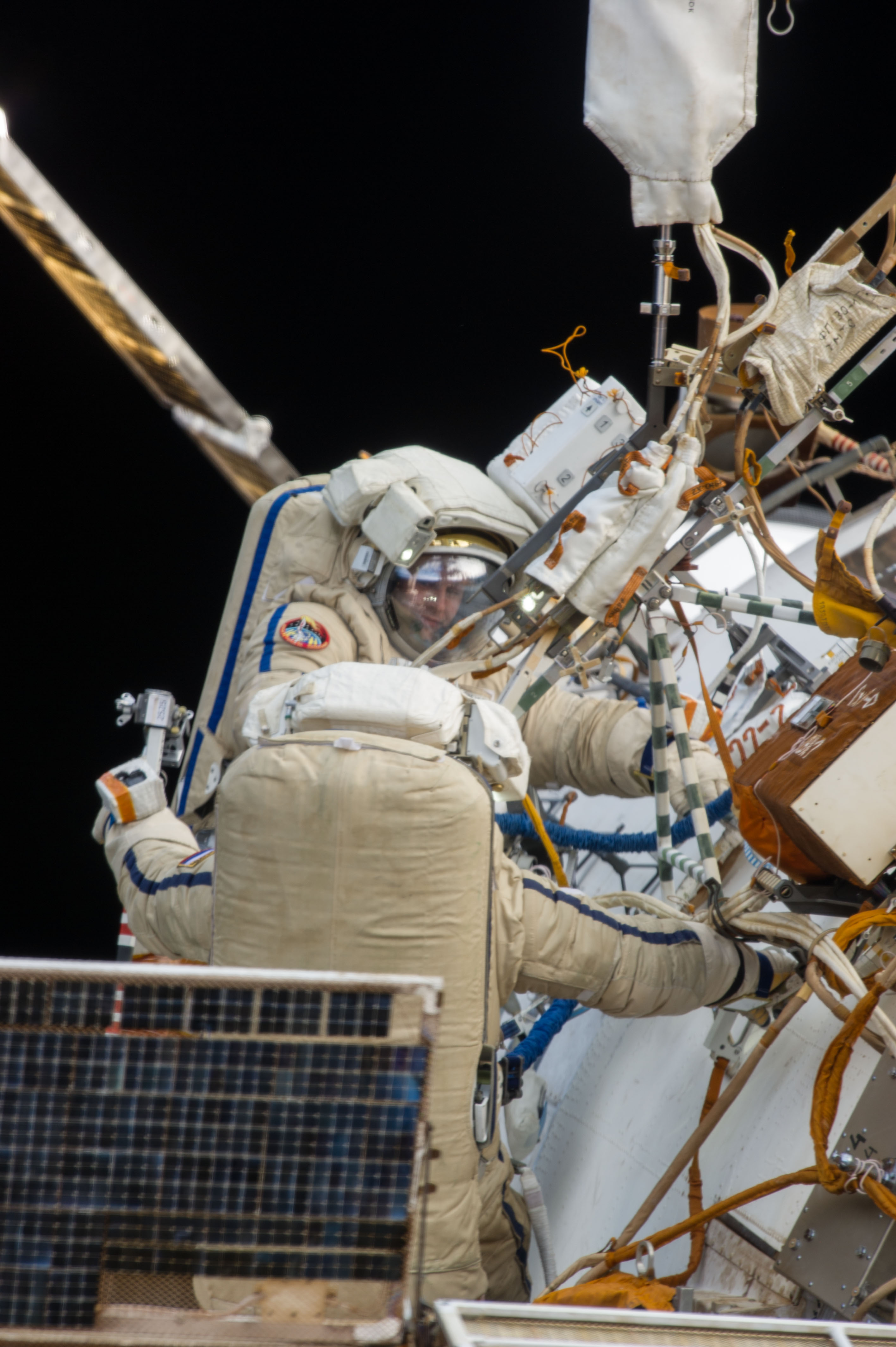 ISS038-E-021696 (27 Dec. 2013) --- Russian cosmonauts Oleg Kotov, Expedition 38 commander; and Sergey Ryazanskiy, flight engineer, attired in Russian Orlan spacesuits, participate in a session of extravehicular activity (EVA) in support of assembly and maintenance on the International Space Station. During the eight-hour, seven-minute spacewalk, Kotov and Ryazanskiy worked with two high-fidelity cameras, removed the Vsplesk experiment package and jettisoned it and replaced it with hardware for a more sophisticated earthquake-monitoring experiment, Seismoprognoz, which they attached to a Zvezda handrail.