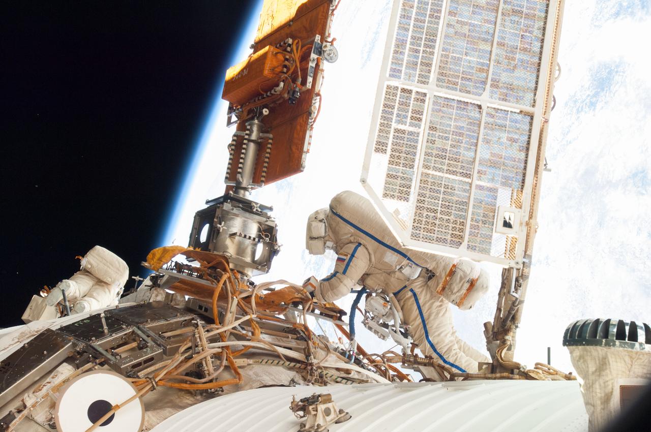 ISS038-E-022882 (27 Dec. 2013) --- Russian cosmonauts Oleg Kotov (right), Expedition 38 commander; and Sergey Ryazanskiy, flight engineer, attired in Russian Orlan spacesuits, participate in a session of extravehicular activity (EVA) in support of assembly and maintenance on the International Space Station. During the eight-hour, seven-minute spacewalk, Kotov and Ryazanskiy worked with two high-fidelity cameras, removed the Vsplesk experiment package and jettisoned it and replaced it with hardware for a more sophisticated earthquake-monitoring experiment, Seismoprognoz, which they attached to a Zvezda handrail.
