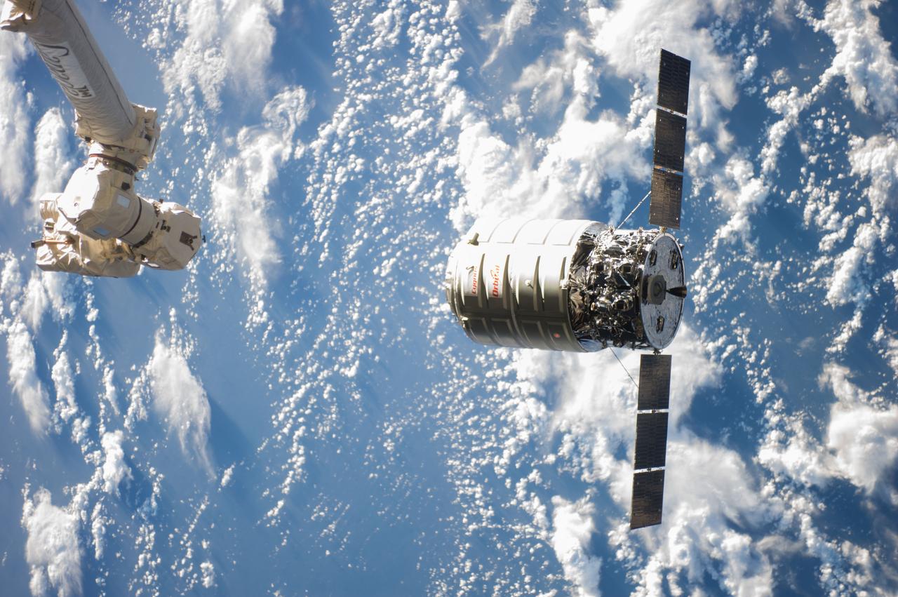 ISS038-E-028035 (12 Jan. 2014) --- The Canadarm2 moves toward the Orbital Sciences Corp. Cygnus commercial cargo craft as it approaches the International Space Station on Jan. 12, 2014. A blue and white part of Earth provides the backdrop for the scene.