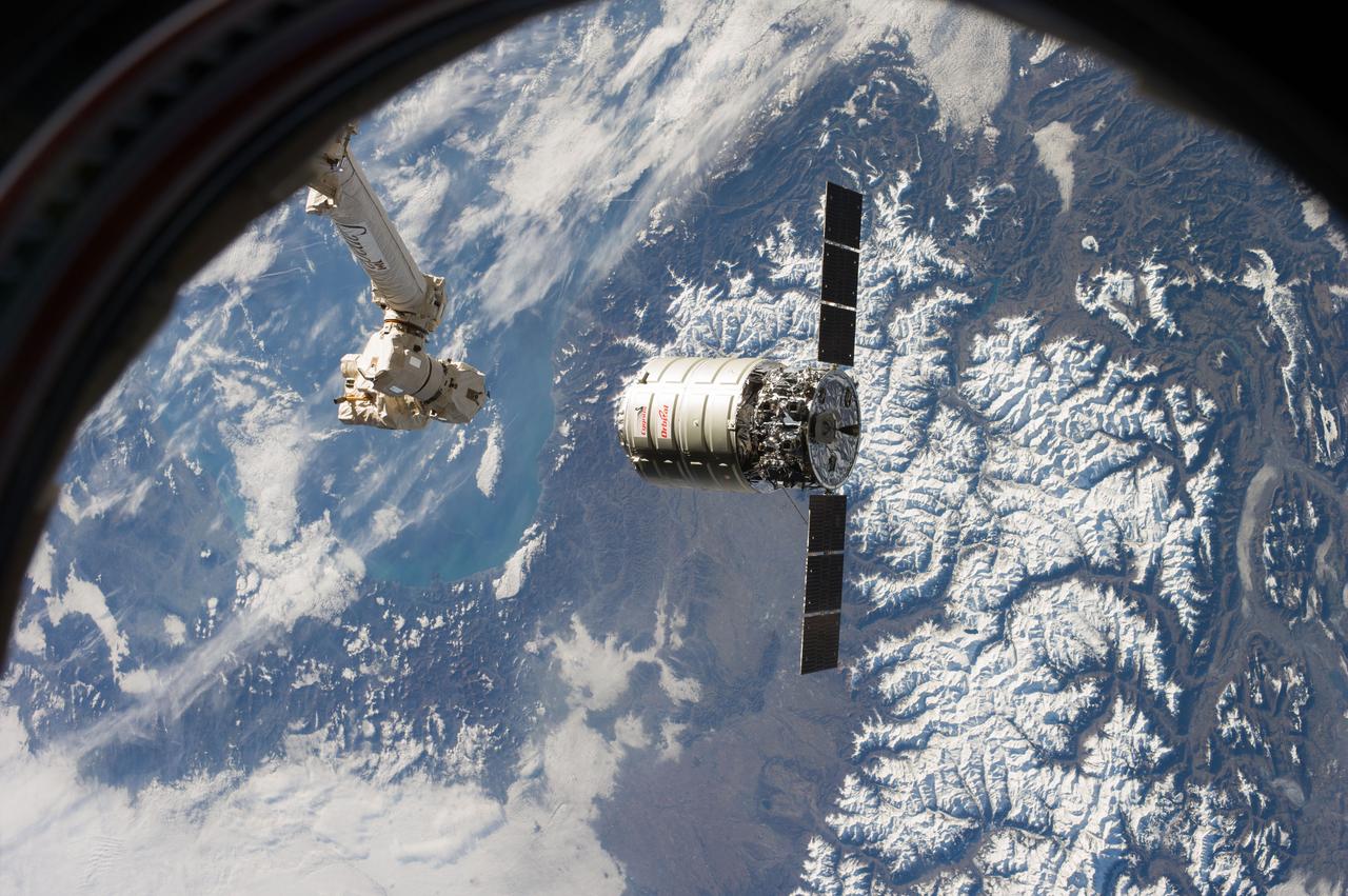 ISS038-E-028044 (12 Jan. 2014) --- The Canadarm2 moves toward the Orbital Sciences Corp. Cygnus commercial cargo craft as it approaches the International Space Station on Jan. 12, 2014. A colorful part of Earth provides the backdrop for the scene.