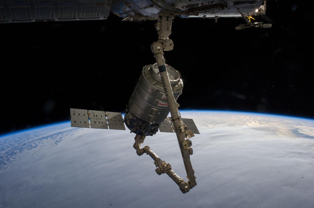 ISS038-E-028071 (12 Jan. 2014) --- The Orbital Sciences Corp. Cygnus commercial cargo craft attached to the end of the Canadarm2 robotic arm of the International Space Station is photographed by an Expedition 38 crew member during rendezvous and berthing operations on Jan. 12, 2014.