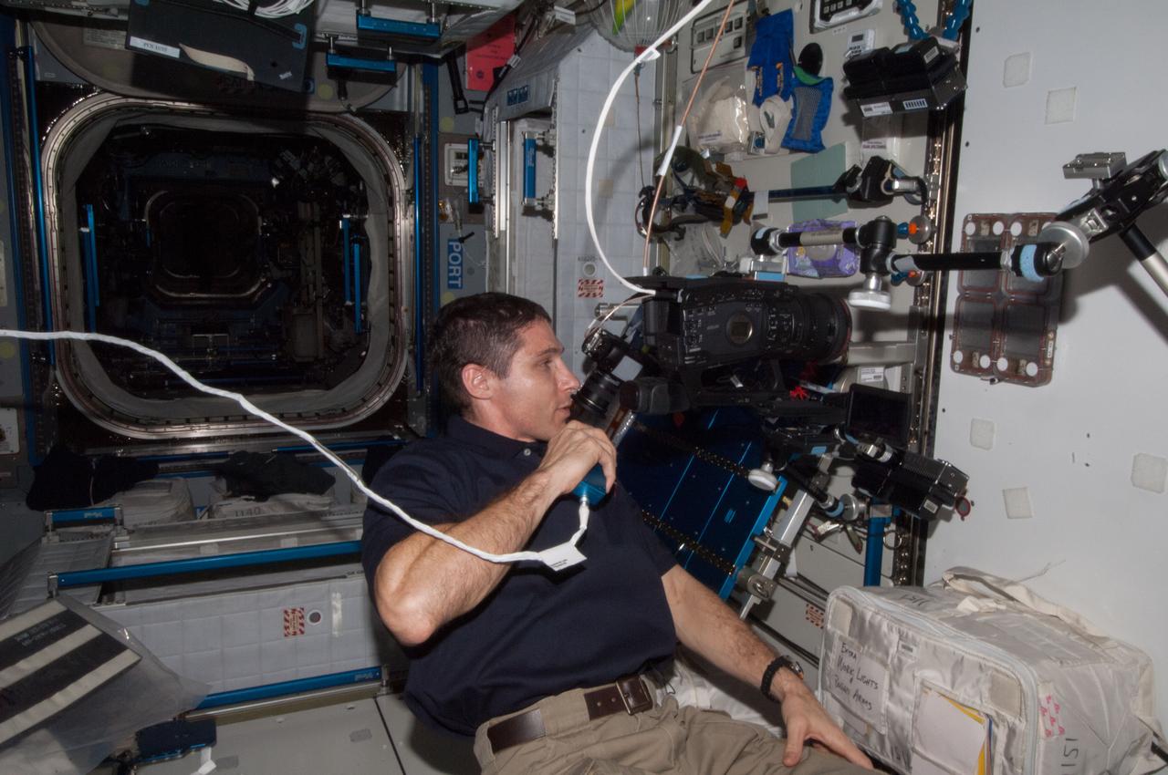 ISS038-E-029065 (12 Jan. 2014) --- In the International Space Station's Destiny laboratory, NASA astronaut Rick Mastracchio, Expedition 38 flight engineer, uses a video camera to photograph the Ant Forage Habitat Facility which will study ant behavior and colonization in microgravity.