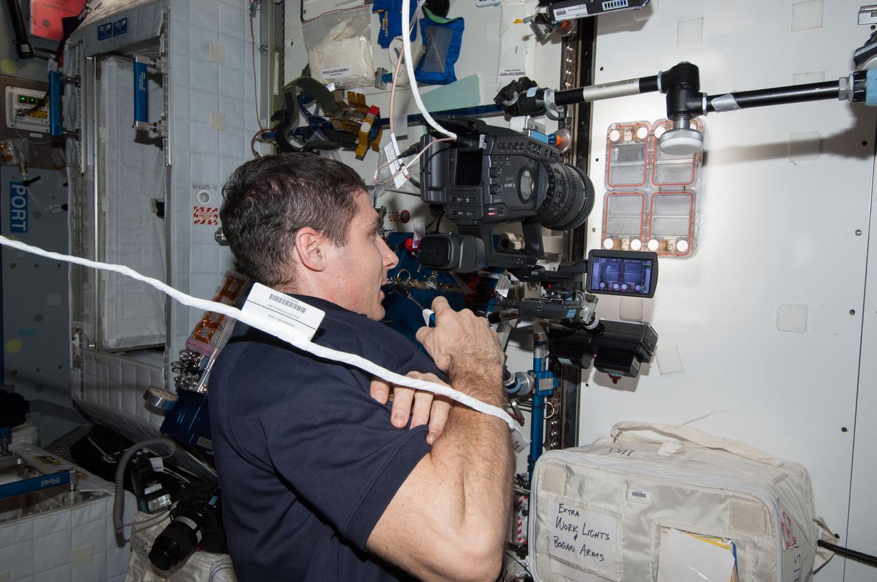 ISS038-E-029077 (12 Jan. 2014) --- In the International Space Station's Harmony node, NASA astronaut Mike Hopkins, Expedition 38 flight engineer, uses a video camera to photograph the Ant Forage Habitat Facility which will study ant behavior and colonization in microgravity.