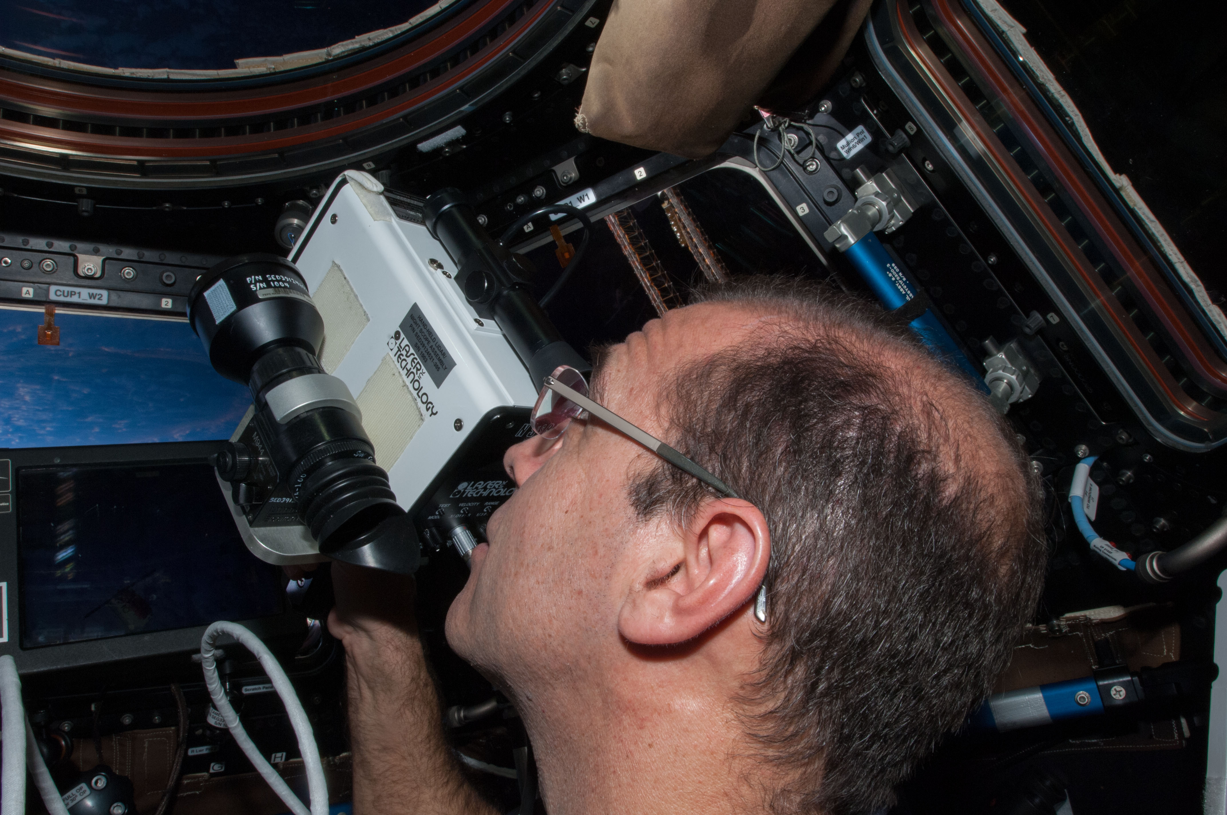 ISS038-E-031969 (12 Jan. 2014) --- At the windows in the International Space Station's Cupola, NASA astronaut Rick Mastracchio, Expedition 38 flight engineer, uses a laser range finder during rendezvous, capture and berthing operations with the Orbital Sciences Corp. Cygnus commercial cargo craft.