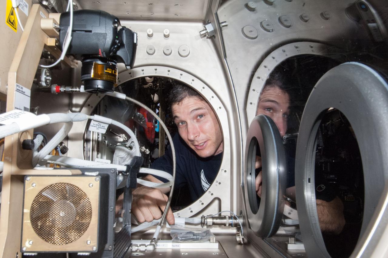 ISS038-E-046393 (12 Feb. 2014) --- NASA astronaut Mike Hopkins, Expedition 38 flight engineer, sets up the Microgravity Science Glovebox (MSG) for the Burning and Suppression of Solids (BASS-II) experiment in the Destiny laboratory of the International Space Station. BASS-II explores how different substances burn in microgravity with benefits for combustion on Earth and fire safety in space.