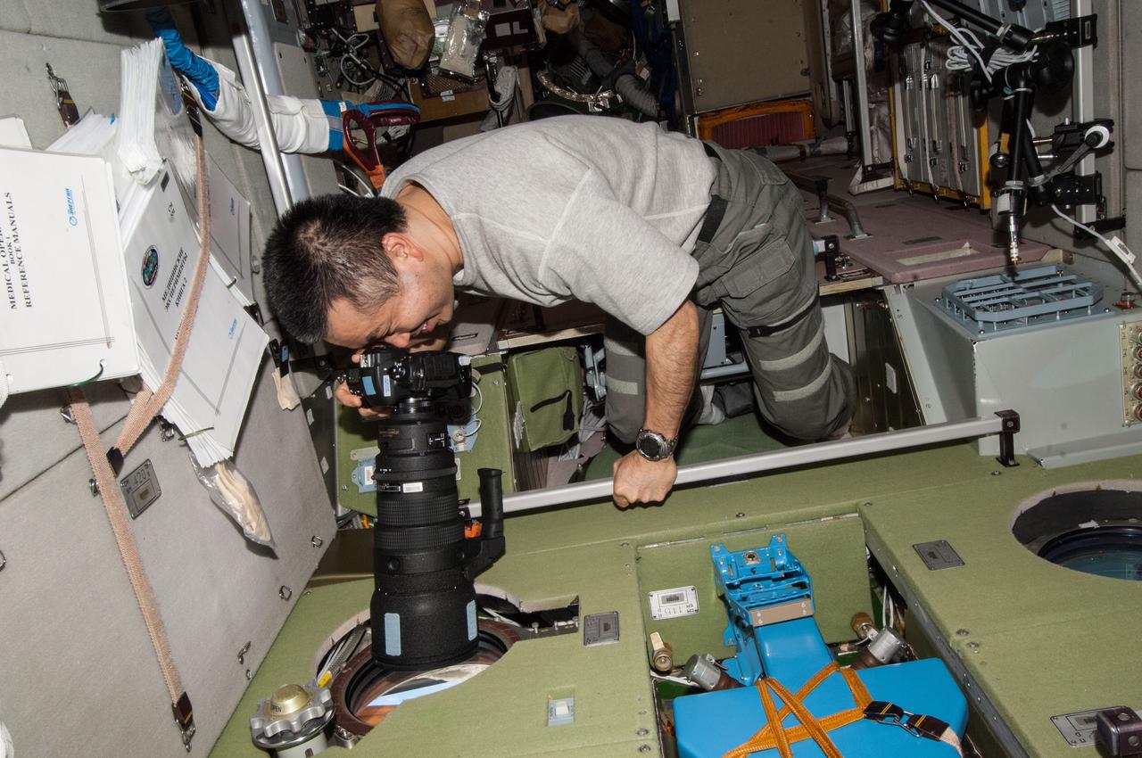 ISS038-E-046880 (13 Feb. 2014) --- Japan Aerospace Exploration Agency astronaut Koichi Wakata, Expedition 38 flight engineer, uses a still camera at a window in the Zvezda Service Module of the International Space Station.