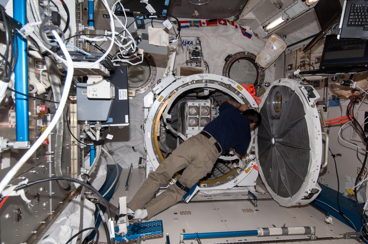 ISS038-E-053258 (19 Feb. 2014) --- In the inner hatch of the International Space Station's Kibo laboratory airlock, Japan Aerospace Exploration Agency astronaut Koichi Wakata, Expedition 38 flight engineer, prepares a second batch of NanoRacks CubeSats for deployment.
