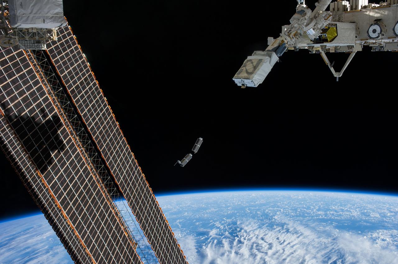 ISS038-E-056389 (25 Feb. 2014) --- A set of NanoRacks CubeSats is photographed by an Expedition 38 crew member after the deployment by the NanoRacks Launcher attached to the end of the Japanese robotic arm. The CubeSats program contains a variety of experiments such as Earth observations and advanced electronics testing. International Space Station solar array panels are at left. Earth's horizon and the blackness of space provide the backdrop for the scene.