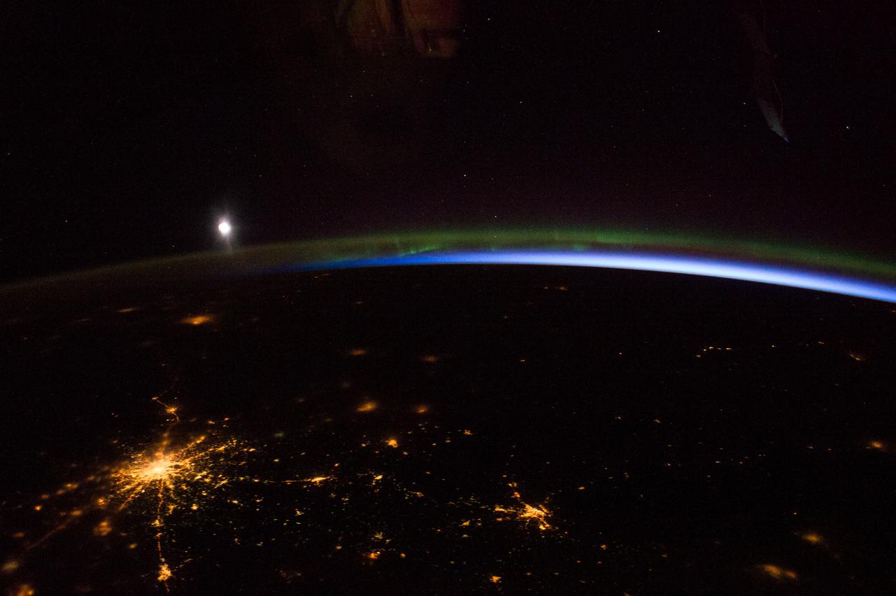 ISS039-E-009160 (2 April 2014) --- This nighttime view featuring the aurora borealis, the moon and Moscow was photographed by an Expedition 39 crew member on the International Space Station. A thin green line of the aurora borealis crosses the top of this image. The moon appears as a white disc just above the aurora. Airglow appears as a blue-white cusp on Earth's limb. Russia's capital city Moscow makes a splash of yellow (lower left), with its easily recognized radial pattern of highways. Other cities are Nizhni Novgorod (lower center) 400 kilometers from Moscow, St. Petersburg (left) 625 kilometers from Moscow, and Finland?s capital city Helsinki.