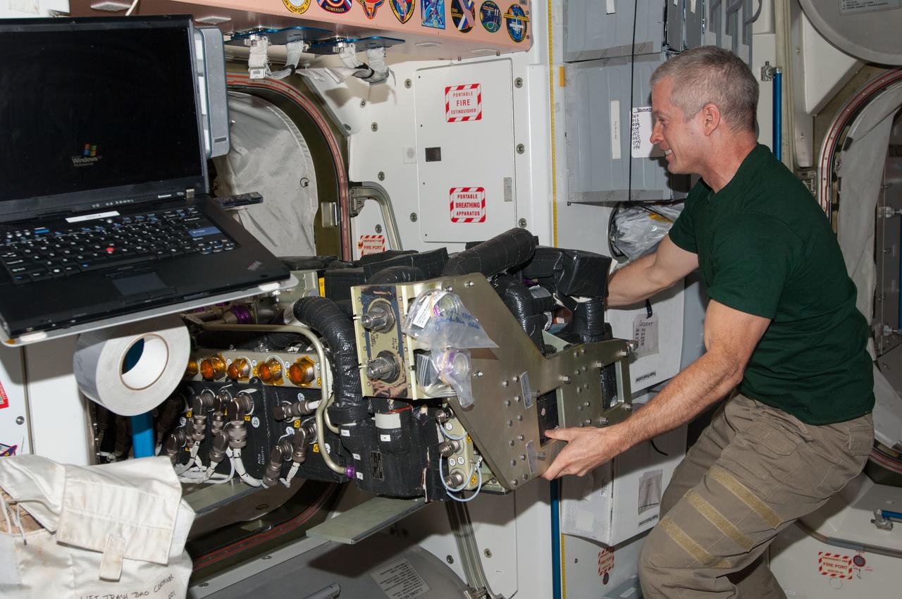 ISS039-E-011054 (10 April 2014) --- NASA astronaut Steve Swanson, Expedition 39 flight engineer, may be smiling because he has the assistance of zero gravity to lift such a large apparatus on the International Space Station.  For several days, the Expedition 39 crew members have been working on a Carbon Dioxide Removal Assembly (CDRA) Desiccant/Adsorbent Bed.
