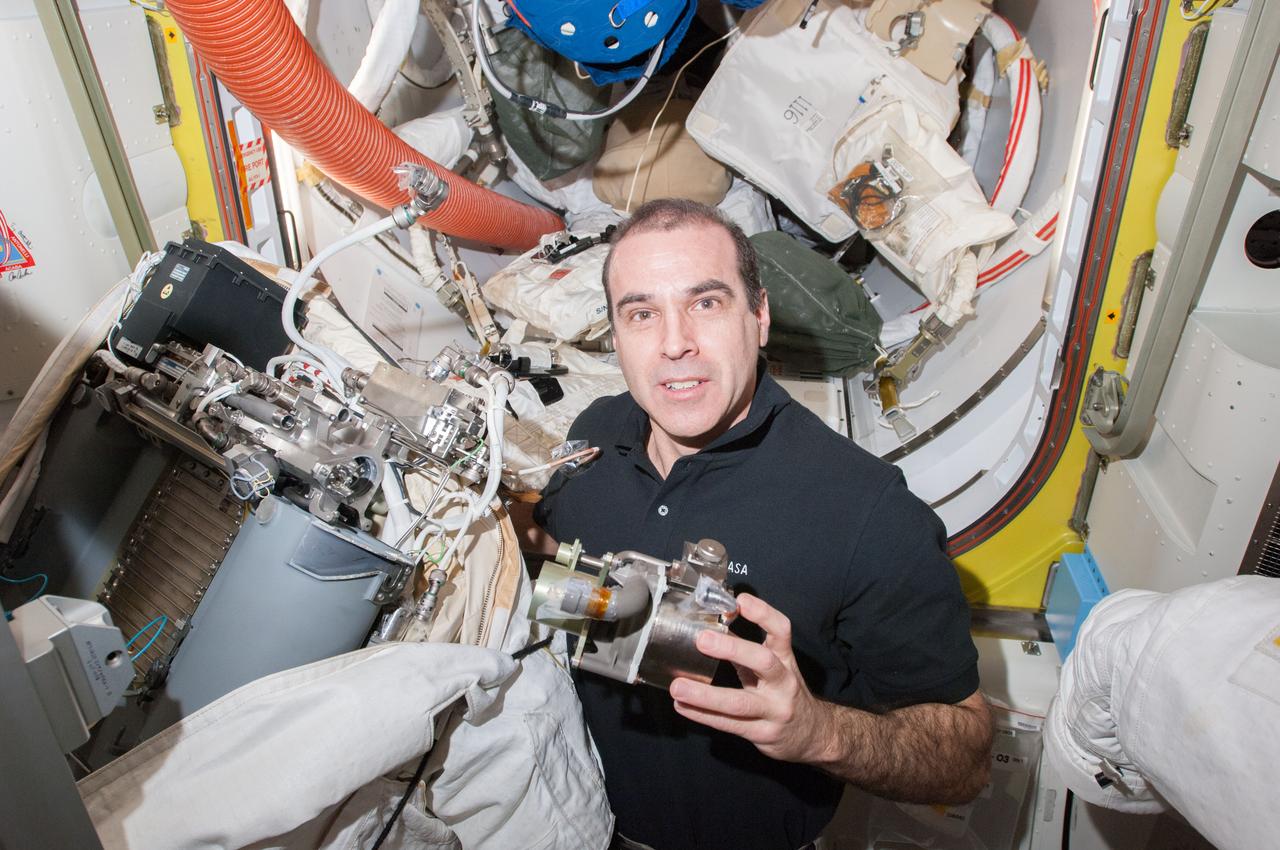 Expedition 39 flight engineer Rick Mastracchio poses for a photo with the replacement Fan Pump Separator (FPS) and Extravehicular Mobility Unit (EMU) 3005. Image was taken in the Quest Airlock (A/L) during FPS remove and replace operations.