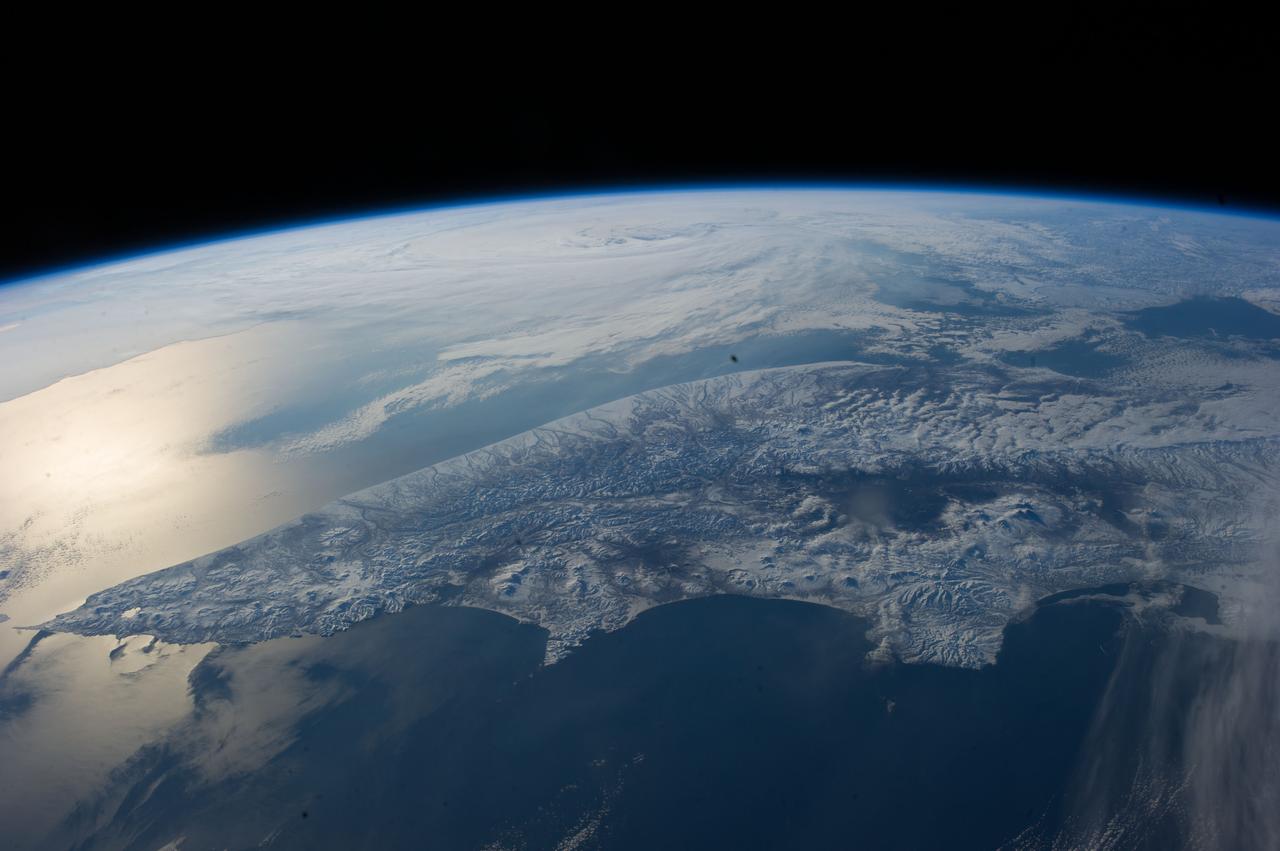 ISS039-E-014807 (22 April 2014) --- As the International Space Station passed over the Bering Sea on Earth Day, one of the Expedition 39 crew members aboard the orbital outpost shot this  panoramic scene looking toward Russia.  The Kamchatka Peninsula can be seen in the foreground.  Sunglint is visible on the left side of the frame.  Only two points of view from Earth orbit were better for taking in this scene than that of the crew member with the camera inside, and those belonged to the two spacewalking astronauts -- Flight Engineers Rick Mastracchio and Steve Swanson of NASA.