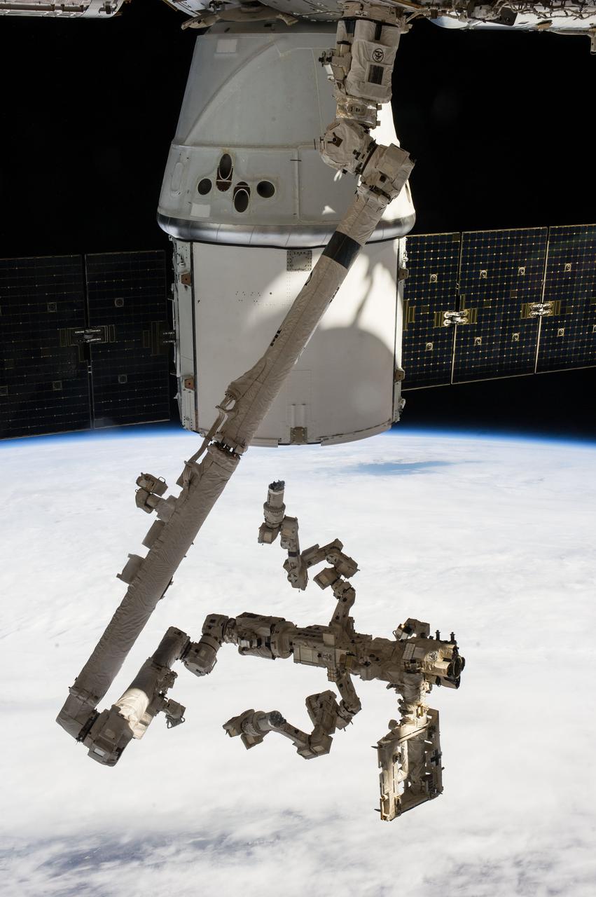 ISS039-E-016800 (30 April 2014) --- Backdropped against a cloudy portion of Earth, the Special Purpose Dexterous Manipulator -- the Canadian Space Agency’s robotic “handyman” AKA Dextre -- and the Canadarm2 or Space Station Remote Manipulator System arm take a "rest" after completing a task 225 miles above the home planet. Robotic ground controllers used the Canadarm2 and Dextre to remove the High Definition Earth Viewing (HDEV) payload from the trunk of the SpaceX Dragon, seen in the top portion of the photo. HDEV was installed on the nadir adapter on the European Space Agency's Columbus exposed facility (out of frame).