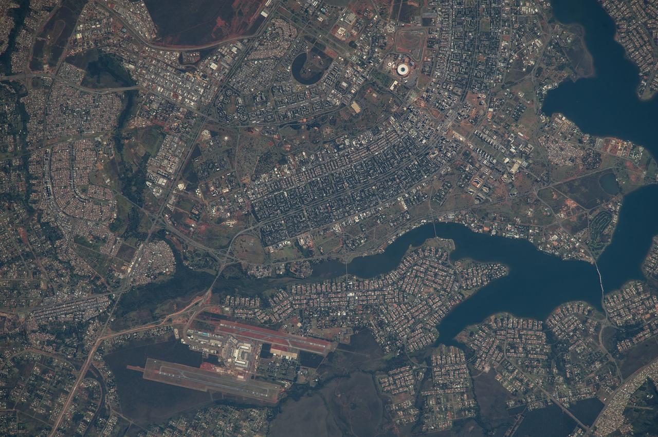 ISS040-E-005839 (28 May 2014) --- The Brasilia World Cup Stadium (top center) is featured in this image photographed by an Expedition 40 crew member on the International Space Station on May 28, 2014. Brazil?s national football stadium, the Estado Nacional, lies near the heart of the capital city of Brasilia. The new roof appears as a brilliant white ring in this image. The stadium is one of Brasilia?s largest buildings. Renovation began in 2010 and it is now the second most expensive stadium in the world, after Wembley Stadium in London, UK. To accommodate expected World Cup fans from all over the world, renovations for all modes of transportation, particularly airports, have been put in place in Brasilia and other host cities. Brasilia?s international airport can be seen lower left on the far side of Lake Paranoa. Brasilia is widely known for its modern building designs and city layout.  Space station crew members have the best view of the city?s well-known ?swept wing? city layout ? giving the sense of a flying bird ? expressed in the curves of the boulevards (top). The stadium occupies the city center between the wings. The President Juscelino Kubitschek Bridge crosses the lake at bottom right. Its 1200-meter span gives scale to the city and stadium.
