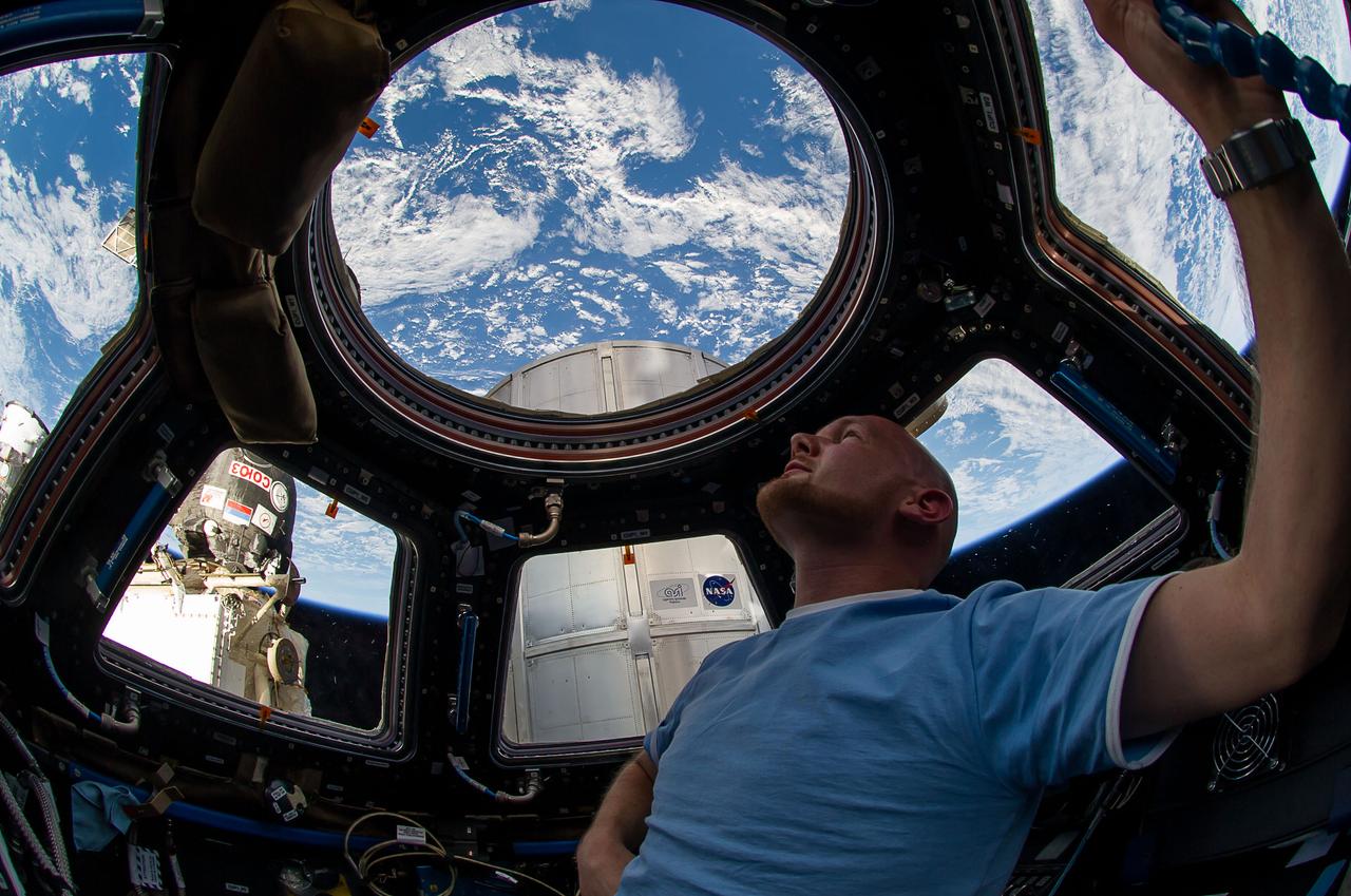 ISS040-E-006197 (1 June 2014) --- European Space Agency astronaut Alexander Gerst, Expedition 40 flight engineer, enjoys the view of Earth from the windows in the Cupola of the International Space Station. A blue and white part of Earth is visible through the windows.