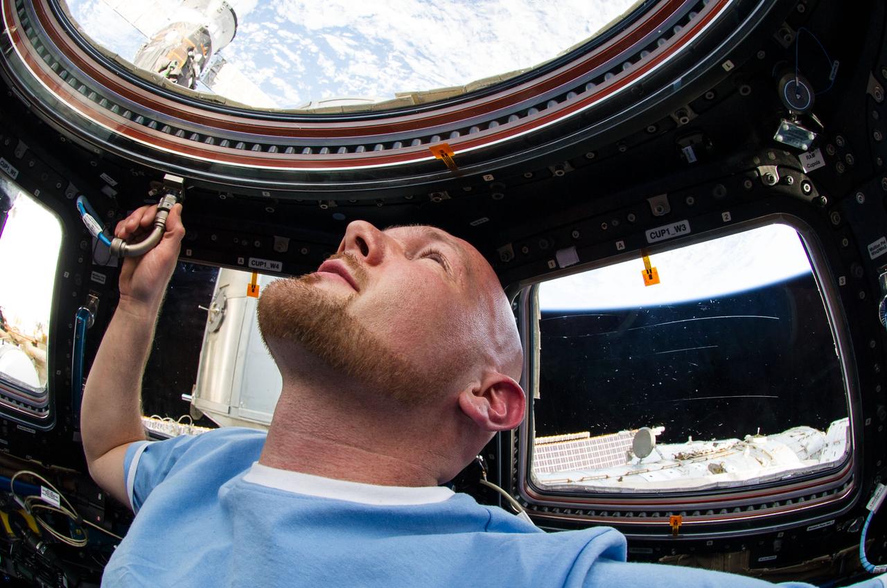 ISS040-E-006199 (1 June 2014) --- European Space Agency astronaut Alexander Gerst, Expedition 40 flight engineer, appears to enjoy his view of Earth through the windows in the Cupola of the International Space Station.