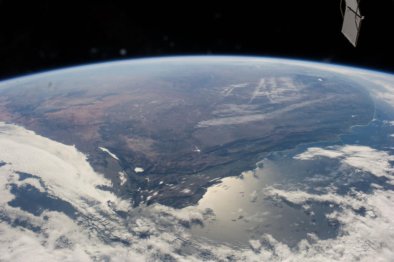ISS040-E-006271 (31 May 2014) --- One of the Expedition 40 crew members aboard the Earth-orbiting International Space Station captured this panoramic image of South Africa on May 31, 2014. A combination of contrails and a bit of winter mist appears to have formed alphabetic and/or numeric characters in the upper right near the horizon. Sun glint off the south coast is slightly confusing as it is similar in brightness to the west-coast cloud cover, where an Atlantic storm rolls in. The Cape Fold Mountains cross the center of the view, going east from the Cape Town region (clouds obscure the Cape peninsula which normally serves as an icon for this part of Africa). A popular winegrowing region attributable to the Mediterranean climate is the area around Cape Town near lower left. Witwatersrand lies at the top of the picture obscured by the seemingly ever-present winter smoke and smog. The Orange River valley appears as a dark, nearly horizontal line at left.