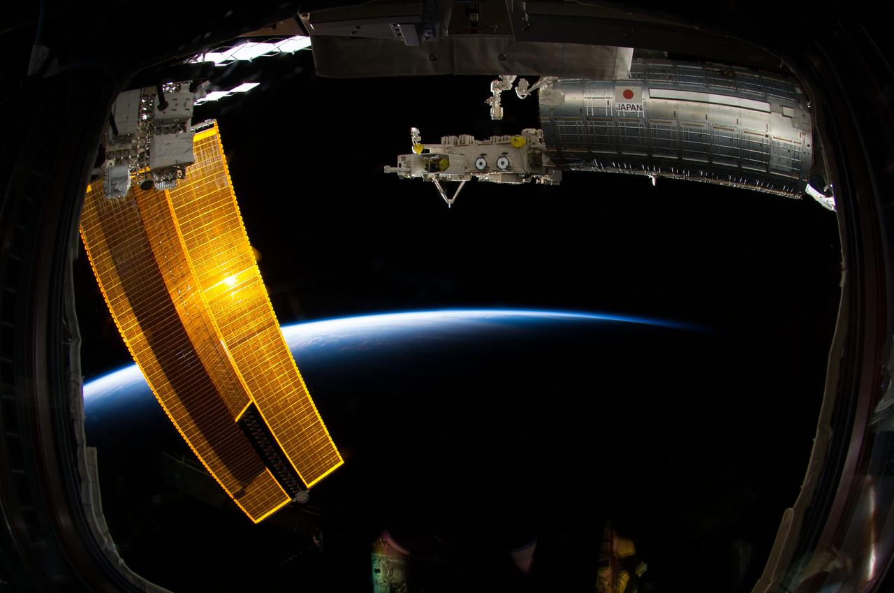 ISS040-E-006510 (1 June 2014) --- Backdropped by the thin line of Earth's atmosphere and the blackness of space, the Japanese Kibo complex of the International Space Station and station solar array wings are featured in this image photographed by an Expedition 40 crew member from a window in the station’s Cupola.
