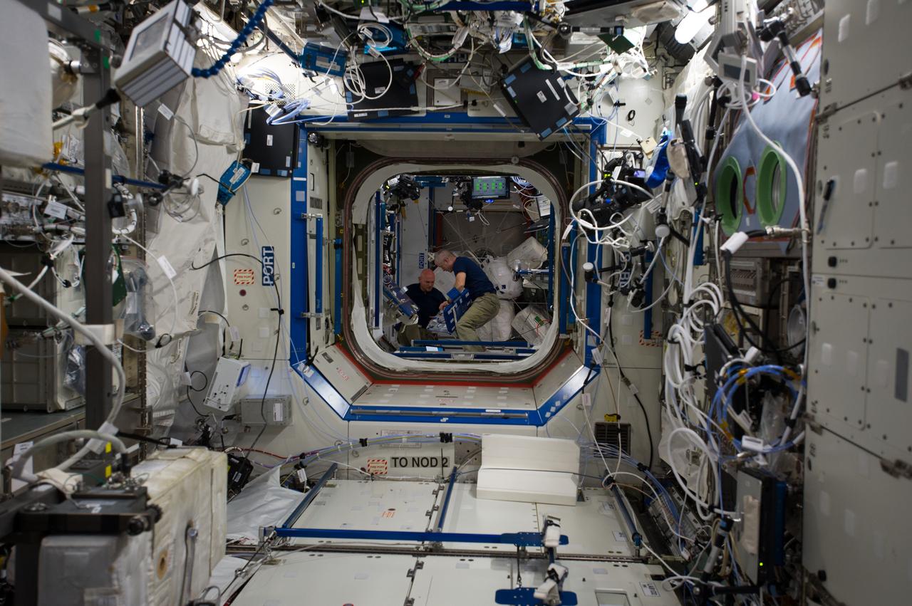 ISS040-E-006696 (2 June 2014) --- NASA astronaut Steve Swanson (right), Expedition 40 commander; and European Space Agency astronaut Alexander Gerst, flight engineer, retrieve items from a medical diagnostic pack in the Harmony node of the International Space Station. The view is taken from the Destiny laboratory.
