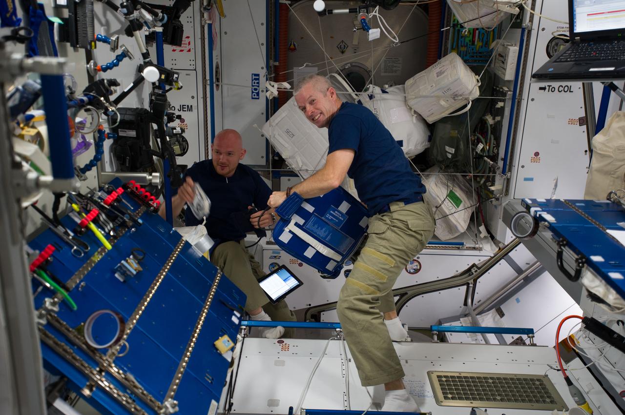 ISS040-E-006697 (2 June 2014) --- NASA astronaut Steve Swanson (right), Expedition 40 commander; and European Space Agency astronaut Alexander Gerst, flight engineer, retrieve items from a medical diagnostic pack in the Harmony node of the International Space Station.