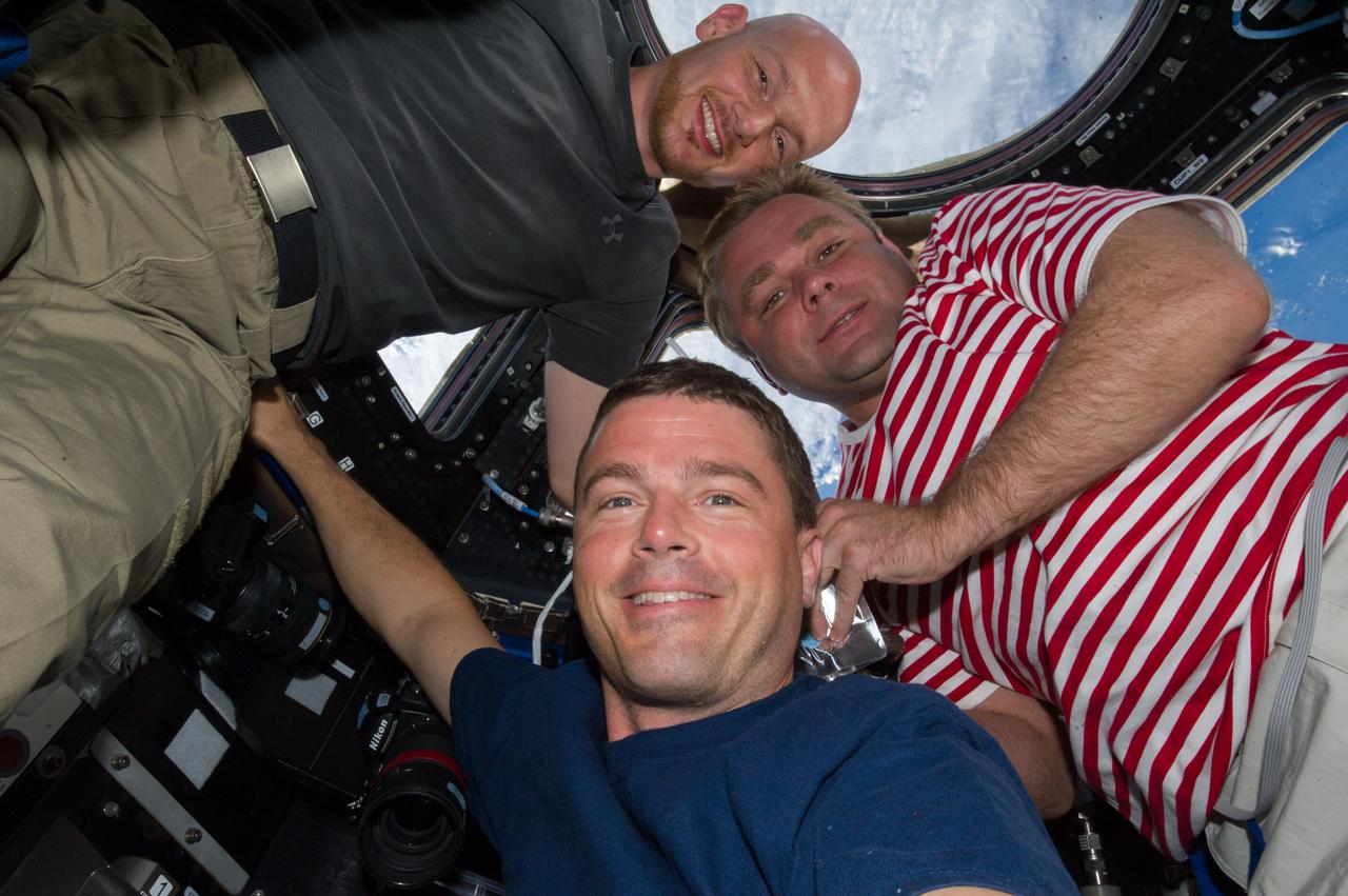 ISS040-E-006724 (2 June 2014) --- European Space Agency astronaut Alexander Gerst (left), NASA astronaut Reid Wiseman (center) and Russian cosmonaut Maxim Suraev, all Expedition 40 flight engineers, pose for a photo in the Cupola of the International Space Station.