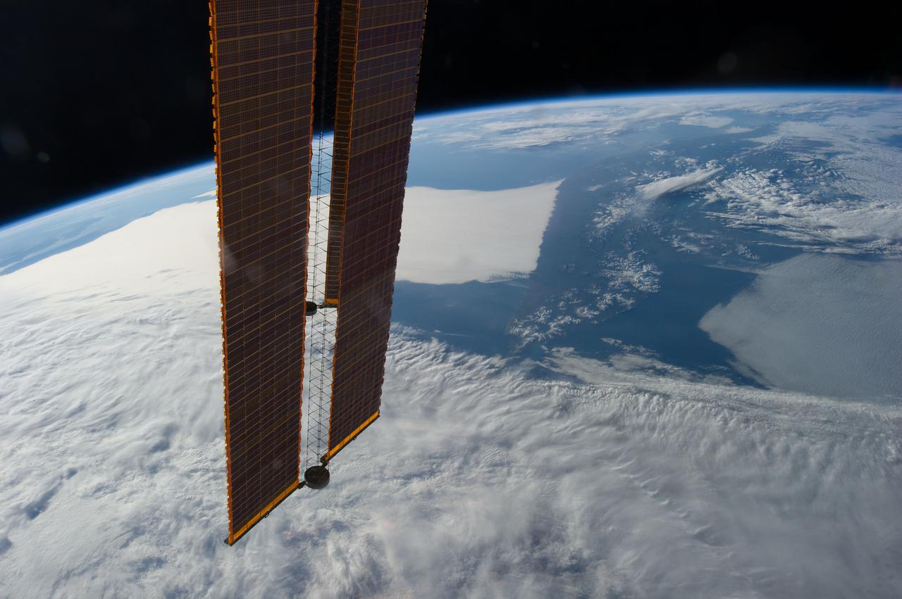 Earth Observation taken during a day pass by the Expedition 40 crew aboard the International Space Station (ISS). Folder lists this as: Moon, Japan, Kamchatka with a wild cloud. Part of a solar array is also visible.