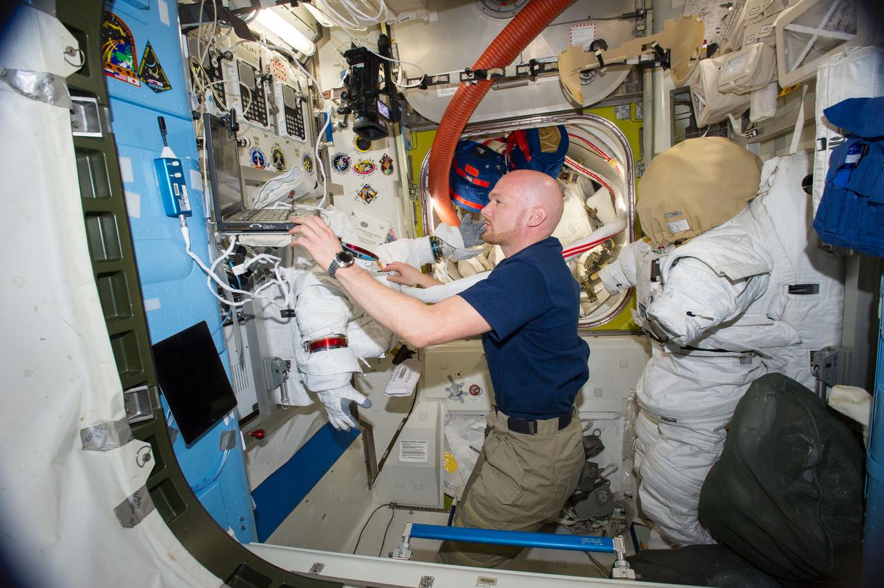 ISS040-E-010972 (12 June 2014) --- European Space Agency astronaut Alexander Gerst, Expedition 40 flight engineer, uses a computer while working on an Extravehicular Mobility Unit (EMU) spacesuit in the Quest airlock of the International Space Station.