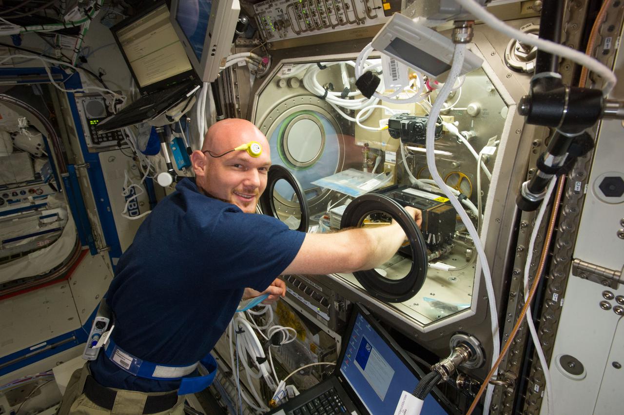 ISS040-E-011005 (13 June 2014) --- European Space Agency astronaut Alexander Gerst, Expedition 40 flight engineer, works with samples and hardware for a combustion experiment known as the Burning and Suppression of Solids (BASS) in the Microgravity Science Glovebox (MSG) in the Destiny laboratory of the International Space Station. He is wearing a Drager Double Sensor on his forehead which is used on the Circadian Rhythms Experiment. This experiment examines the hypothesis that long-term spaceflights significantly affect the synchronization of the circadian rhythms in humans due to changes of a non-24 hour light-dark cycle.