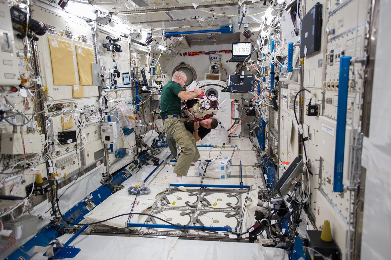 ISS040-E-014147 (18 June 2014) --- In the International Space Station's Kibo laboratory, NASA astronauts Steve Swanson (foreground), Expedition 40 commander; and Reid Wiseman, flight engineer, conduct test runs of the SPHERES-Slosh experiment, using the soccer-ball-sized, free-flying satellites known as Synchronized Position Hold, Engage, Reorient, Experimental Satellites, or SPHERES. The SPHERES-Slosh investigation uses small robotic satellites on the space station to examine how liquids move around inside containers in microgravity.