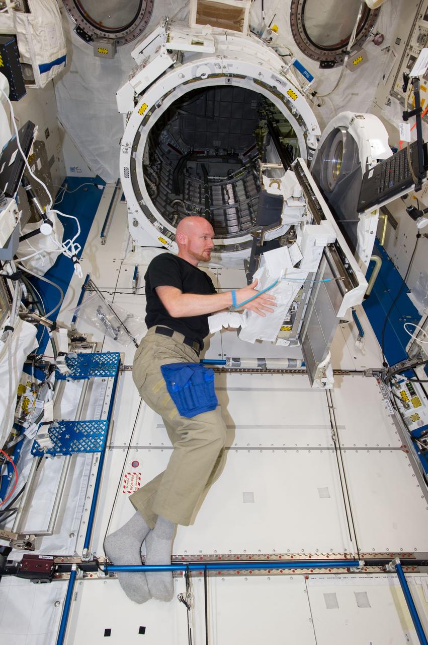 ISS040-E-019307 (25 June 2014) --- In the International Space Station?s Kibo laboratory, European Space Agency astronaut Alexander Gerst, Expedition 40 flight engineer, prepares to transfer a multi-purpose experiment platform and a robotic arm known as the Small Fine Arm through the Kibo module?s scientific airlock. The Small Fine Arm, which attaches to the Kibo?s larger main arm, handles delicate operations involved in exchanging experiments and payloads located on the Exposed Facility.