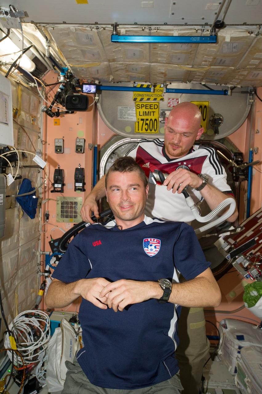ISS040-E-020384 (26 June 2014) --- European Space Agency astronaut Alexander Gerst, Expedition 40 flight engineer, shaves the head of NASA astronaut Reid Wiseman, flight engineer, in the Unity node of the International Space Station. Gerst used hair clippers fashioned with a vacuum device to garner freshly cut hair. A friendly World Cup Soccer-related agreement between the crew members representing the USA, and Gerst, a German citizen who represents the European Space Agency, called for the American losers of a German-USA match to have their heads shaved. The German team won the match 1-0.