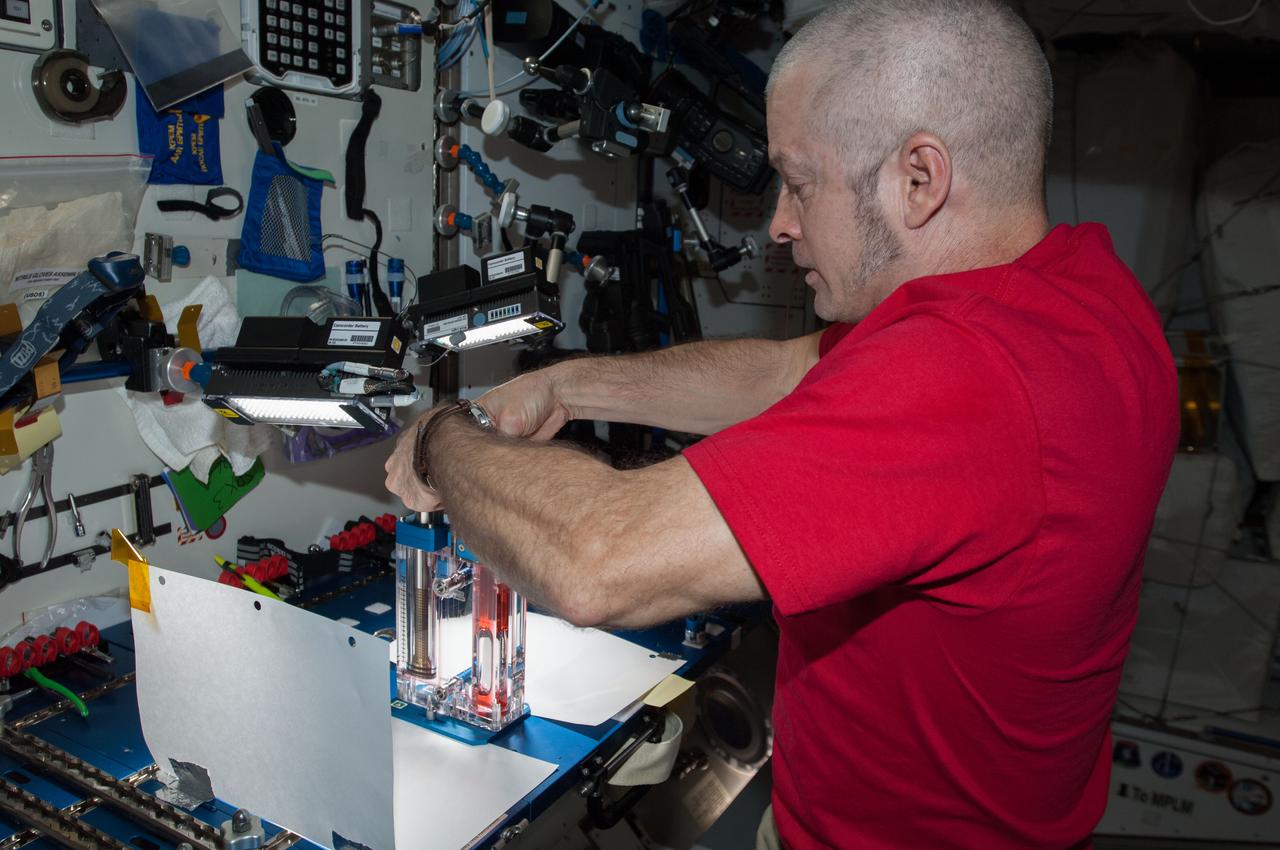 ISS040-E-032820 (3 July 2014) --- NASA astronaut Steve Swanson, Expedition 40 commander, conducts a session with the Capillary Flow Experiment (CFE) in the Harmony node of the International Space Station. CFE is a suite of fluid physics experiments that investigate how fluids move up surfaces in microgravity. The results aim to improve current computer models that are used by designers of low gravity fluid systems and may improve fluid transfer systems for water on future spacecraft.