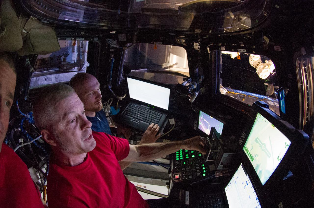 ISS040-E-055101 (9 July 2014) --- In the International Space Station?s Cupola, NASA astronaut Steve Swanson, Expedition 40 commander; and European Space Agency astronaut Alexander Gerst (background), flight engineer, practice grapple procedures with the Canadarm2 in preparation for the upcoming arrival of the Orbital Sciences? Cygnus cargo craft.