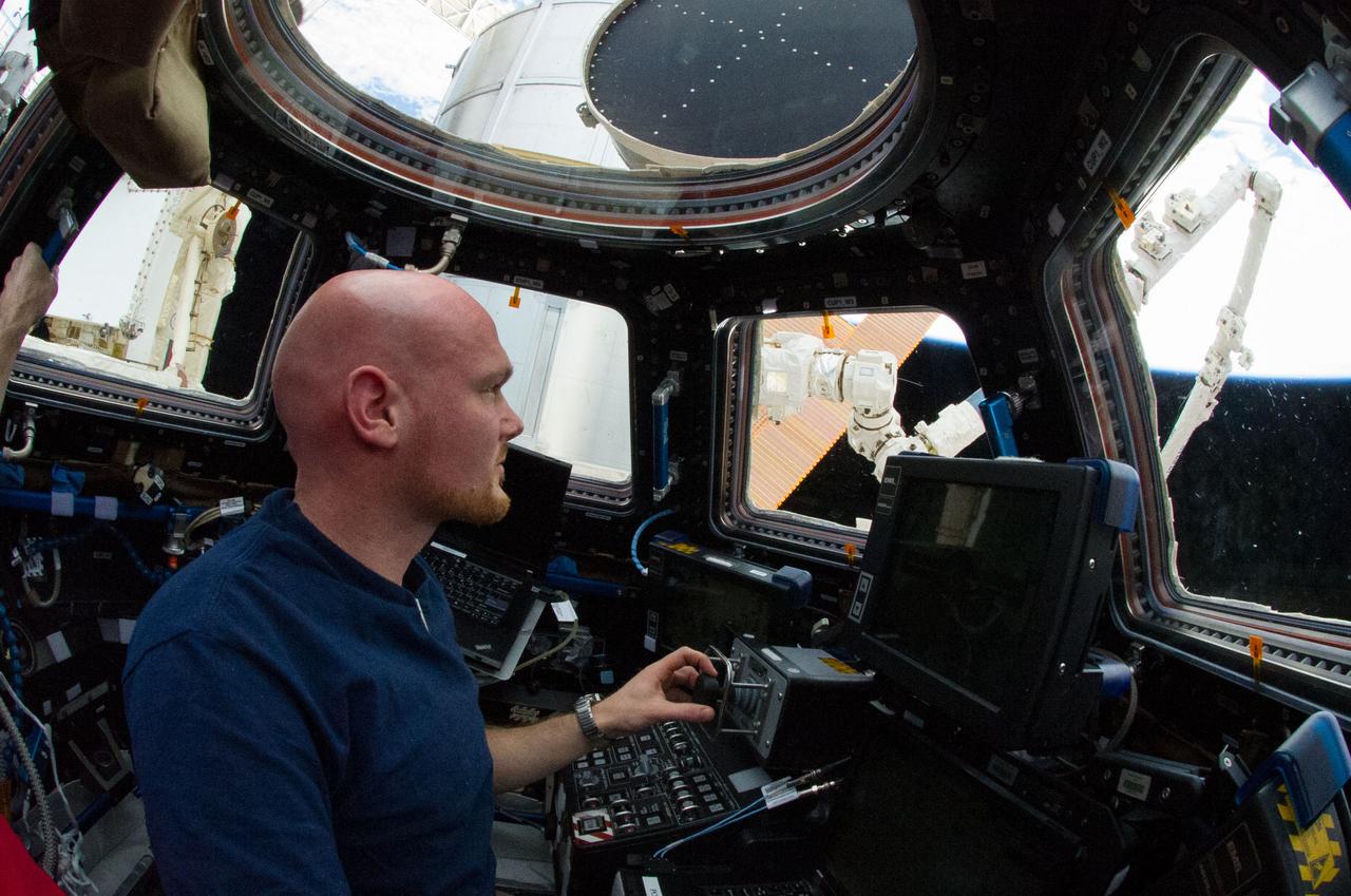 ISS040-E-055166 (9 July 2014) --- In the International Space Station?s Cupola, European Space Agency astronaut Alexander Gerst, Expedition 40 flight engineer, practices grapple procedures with the Canadarm2 in preparation for the upcoming arrival of the Orbital Sciences? Cygnus cargo craft.