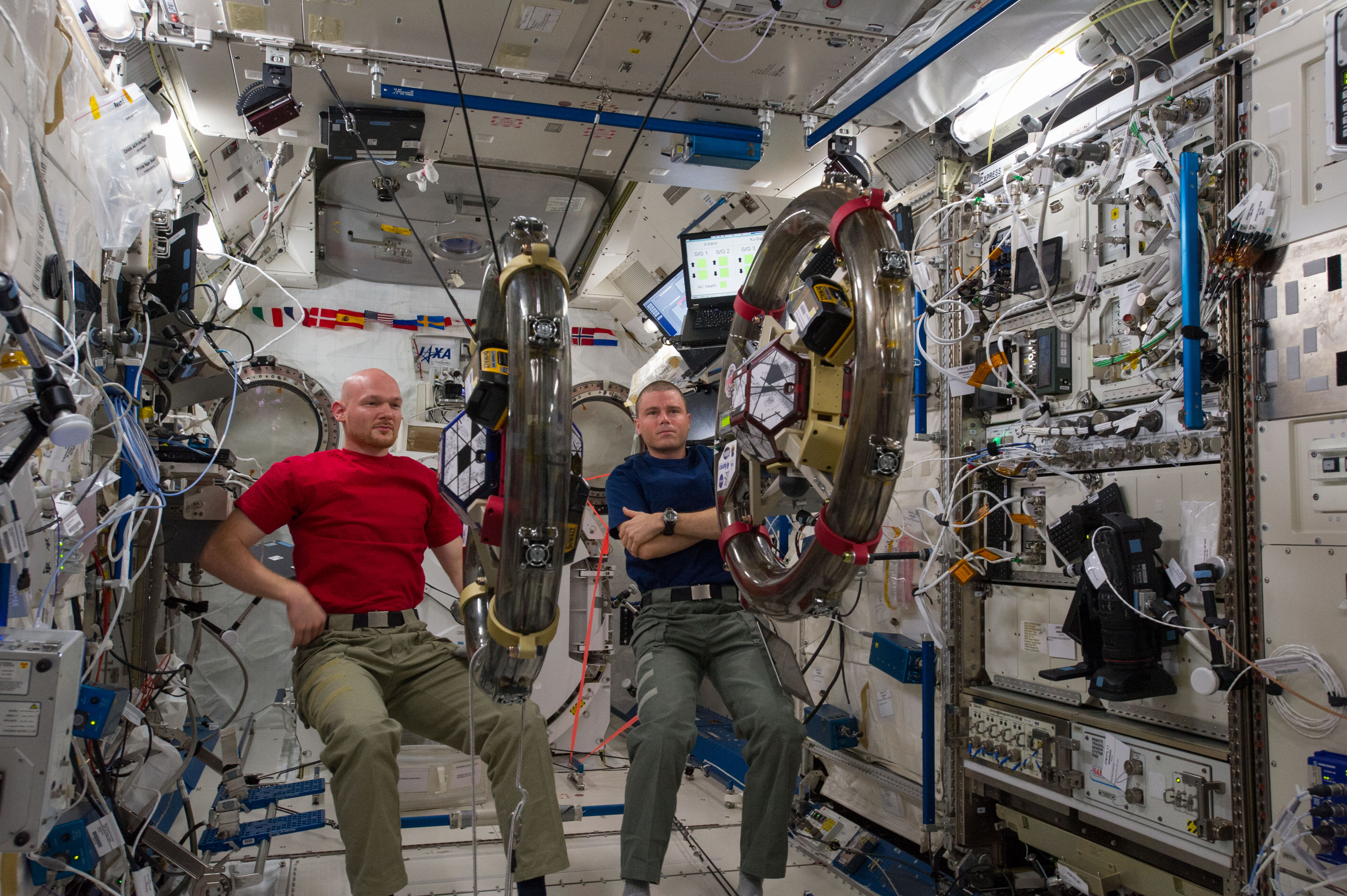 ISS040-E-059478 (10 July 2014) --- In the International Space Station's Kibo laboratory, European Space Agency astronaut Alexander Gerst (left) and NASA astronaut Reid Wiseman, both Expedition 40 flight engineers, conduct a session with a pair of bowling-ball-sized free-flying satellites known as Synchronized Position Hold, Engage, Reorient, Experimental Satellites, or SPHERES. Surrounding the two SPHERES mini-satellites is ring-shaped hardware known as the Resonant Inductive Near-field Generation System, or RINGS. SPHERES-RINGS seeks to demonstrate wireless power transfer between satellites at a distance for enhanced operations.