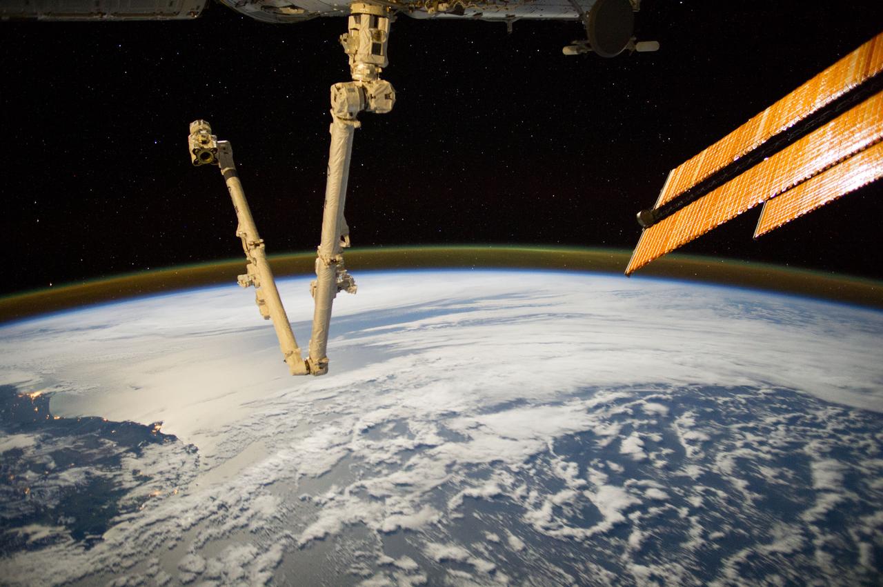 Earth Observation taken during a night pass by the Expedition 40 crew aboard the International Space Station (ISS). Folder lists this as: HDR night series (New Zealand pass). The Space Station Remote Manipulator System (SSRMS) arm is visible. Aurora visible over Earth limb.