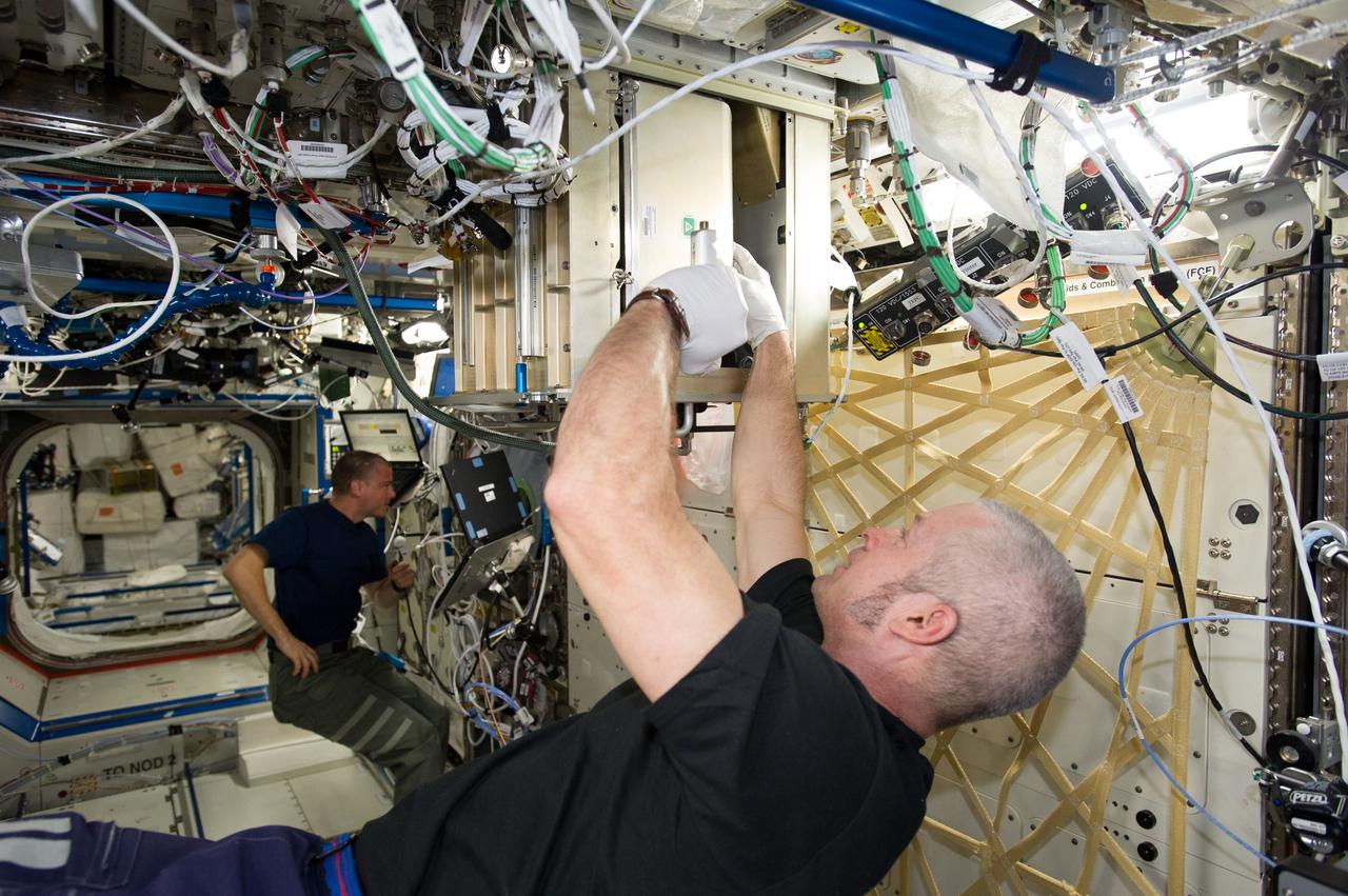 ISS040-E-064624 (15 July 2014) --- NASA astronaut Steve Swanson, Expedition 40 commander, replaces filters in the Potable Water Dispenser (PWD) in the Destiny laboratory of the International Space Station. NASA astronaut Reid Wiseman, flight engineer, works in the background.