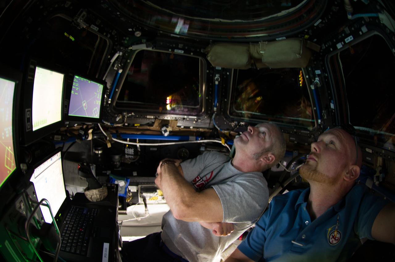ISS040-E-067869 (16 July 2014) --- NASA astronaut Steve Swanson (left), Expedition 40 commander; and European Space Agency astronaut Alexander Gerst, flight engineer, are pictured in the International Space Station?s Cupola during rendezvous and capture operations of the Orbital Sciences? Cygnus cargo craft.