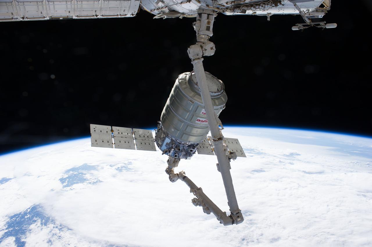 ISS040-E-067895 (16 July 2014) --- The Orbital Sciences’ Cygnus cargo craft attached to the end of the Canadarm2 robotic arm of the International Space Station is photographed by an Expedition 40 crew member after the two spacecraft converged at 6:36 a.m. (EDT) on July 16, 2014. A blue and white part of Earth and the blackness of space provide the backdrop for the scene.