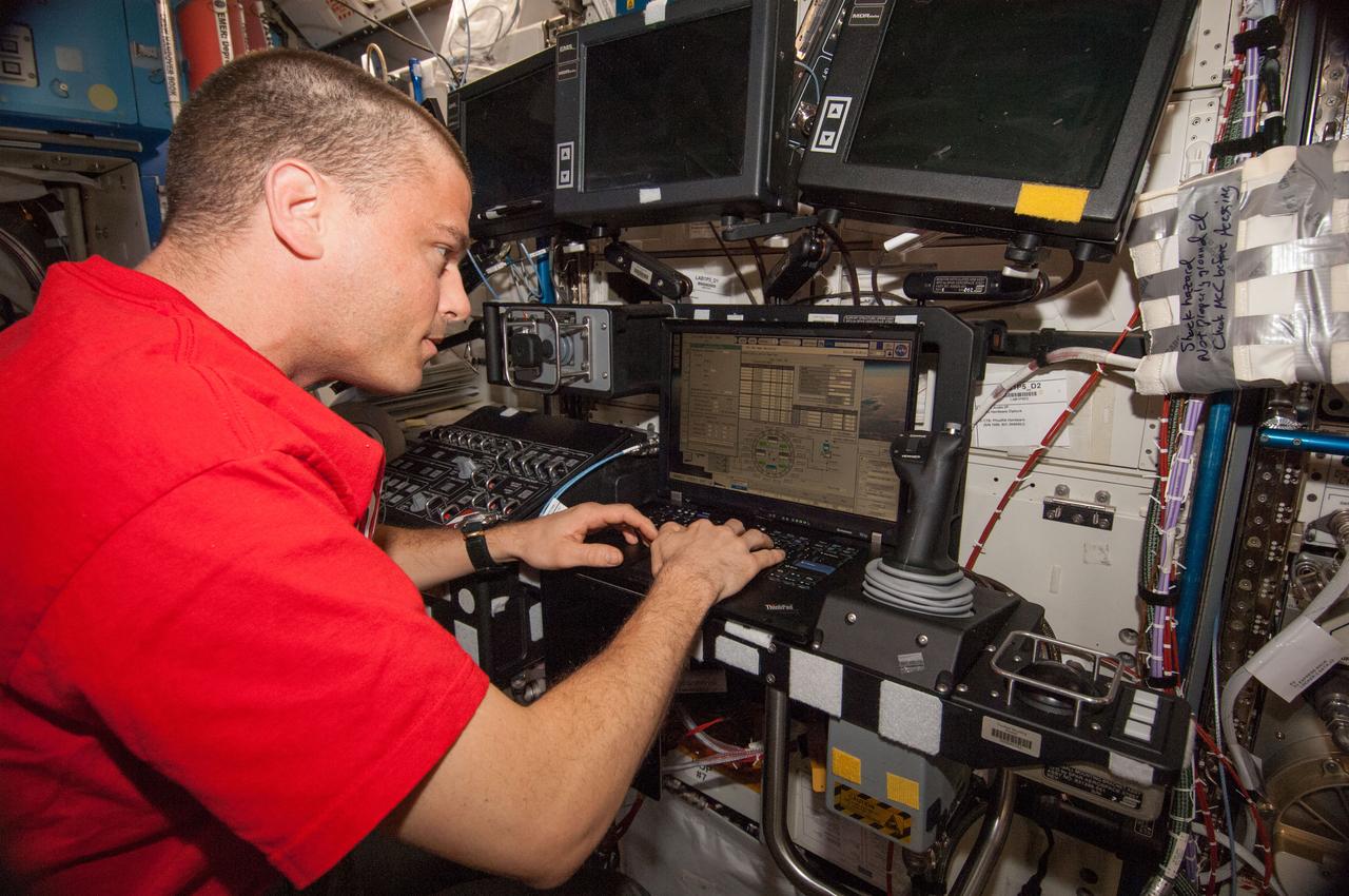 Astronaut Reid Wiseman,Expedition 40 flight engineer,is photographed at the Space Station Remote Manipulator System (SSRMS) arm controls in the U.S. Laboratory during the capture and berthing of the Cygnus spacecraft.