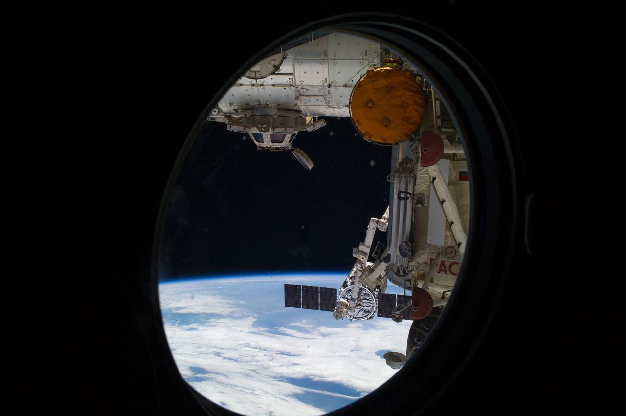 ISS040-E-068661 (16 July 2014) --- Looking through a window on the International Space Station, the capture of the Orbital Sciences? Cygnus cargo craft by the station?s Canadarm2 is photographed by an Expedition 40 crew member onboard the station. The two spacecraft converged at 6:36 a.m. (EDT) on July 16, 2014. Also visible in this image are the station?s Cupola and the Tranquility node (top). A blue and white part of Earth and the blackness of space provide the backdrop for the scene.