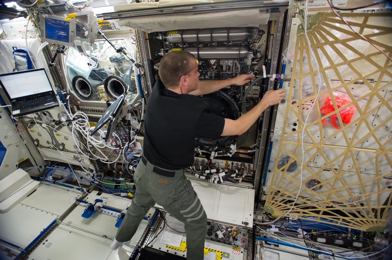 ISS040-E-071994 (21 July 2014) --- In the International Space Station’s Destiny laboratory, NASA astronaut Reid Wiseman, Expedition 40 flight engineer, sets up the Combustion Integrated Rack (CIR) for more ground-commanded tests. This facility, which includes an optics bench, combustion chamber, fuel and oxidizer control and five different cameras, allows a variety of combustion experiments to be performed safely aboard the station.
