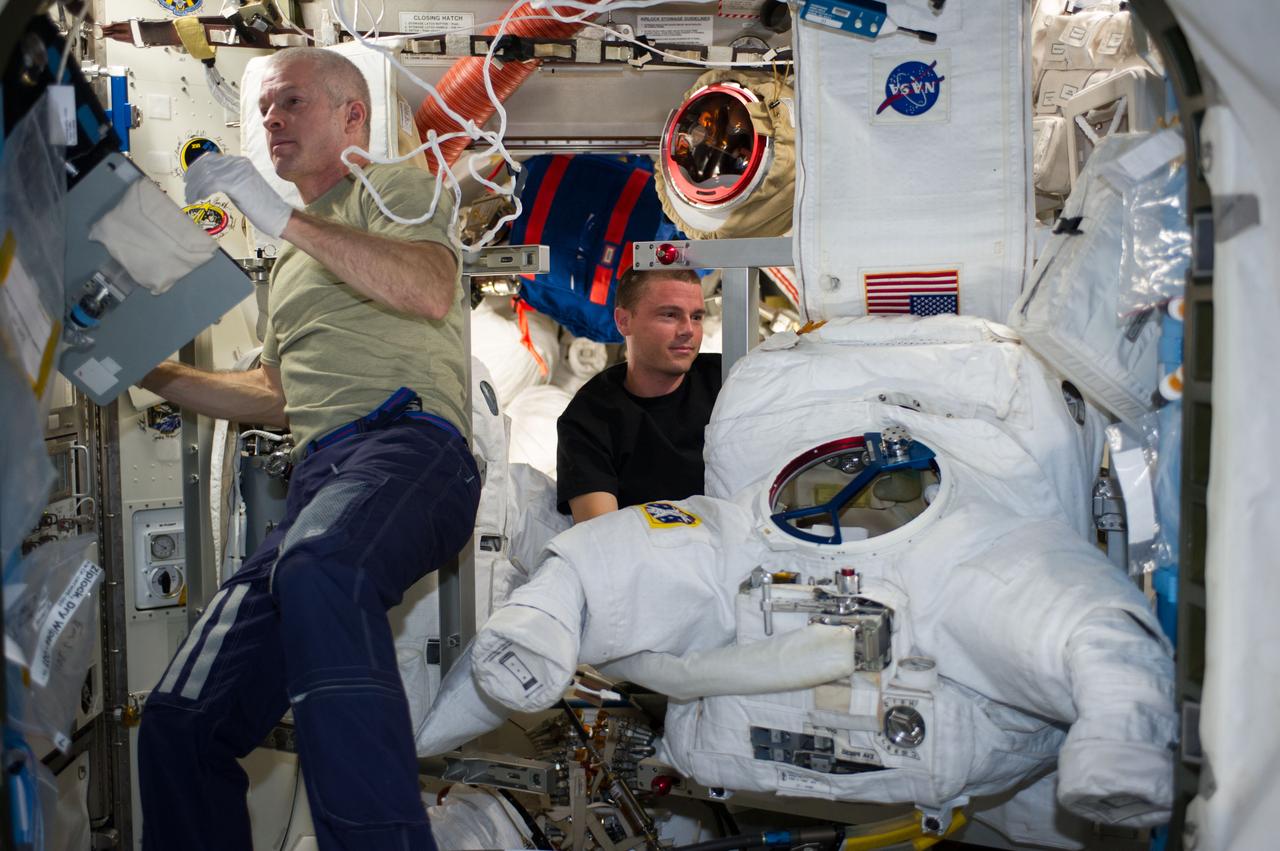 ISS040-E-080767 (28 July 2014) --- NASA astronauts Steve Swanson (left), Expedition 40 commander, and Reid Wiseman, flight engineer, work in tandem to perform in-flight maintenance on an Extravehicular Mobility Unit (EMU) spacesuit in the Quest airlock of the International Space Station.