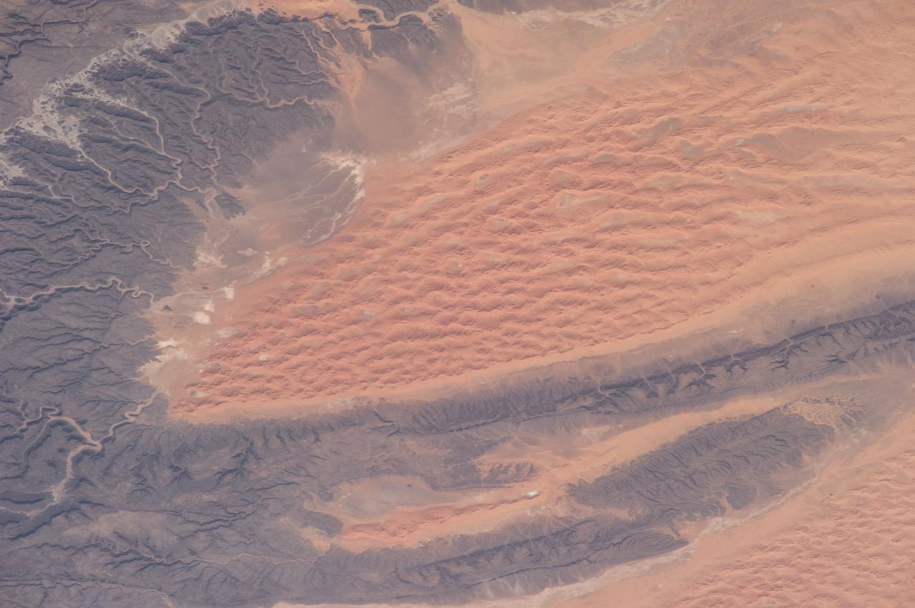 ISS040-E-081008 (25 July 2014) --- One of the Expedition 40 crew members aboard the International Space Station, flying 225 nautical miles above Earth, photographed this image of the Tifernine dunes and the Tassili Najjer Mountains in Algeria. The area is about 800 miles south, southeast of Algiers, the capital of Algeria. The dunes are in excess of 1,000 feet in height.