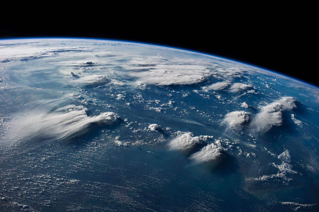ISS040-E-088891 (5 Aug. 2014) --- Thunderheads near Borneo, Indonesia are featured in this image photographed by an Expedition 40 crew member on the International Space Station. Late afternoon sun casts long shadows from high thunderhead anvils over southern Borneo. Crews aboard the space station have recently concentrated on panoramic views of clouds?taken with lenses similar to the focal length of the human eye. These images reveal the kinds of views crews see -- huge areas of the planet, with a strong three-dimensional sense of what it is like to fly 350 kilometers above Earth. Winds usually blow in different directions at different altitudes.  High-altitude winds are clearly sweeping the tops off the many tallest thunderclouds, generating long anvils of diffuse cirrus plumes that trail south. At low levels, ?streets? of white dots -- fair-weather cumulus clouds -- are aligned with west-moving winds (lower left). Small smoke plumes from forest fires onshore are also aligned west. Storm formation near the horizon -- more than 1,000 kilometers away (center) -- is assisted by air currents rising over the central mountains of Borneo.