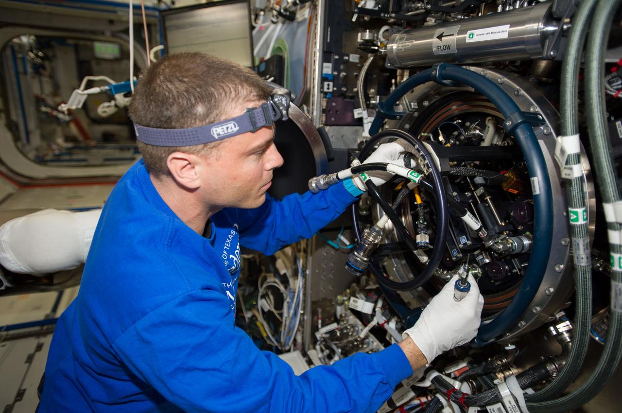 ISS040-E-090484 (11 Aug. 2014) --- NASA astronaut Reid Wiseman, Expedition 40 flight engineer, performs routine in-flight maintenance on the Multi-user Drop Combustion Apparatus (MDCA) inside the Combustion Integrated Rack (CIR) in the Destiny laboratory of the International Space Station. The MDCA contains hardware and software to conduct unique droplet combustion experiments in space.