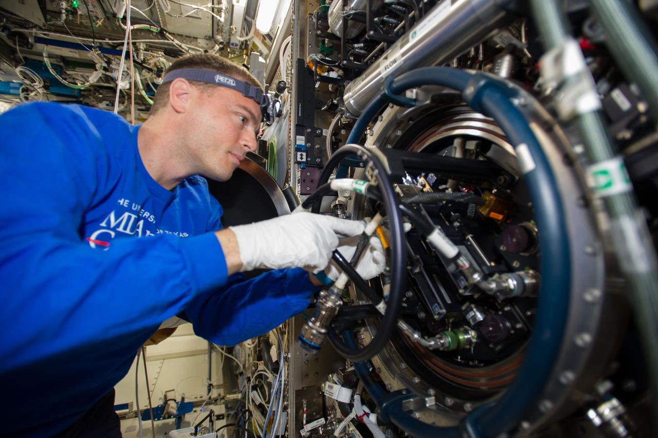 ISS040-E-090497 (11 Aug. 2014) --- NASA astronaut Reid Wiseman, Expedition 40 flight engineer, performs routine in-flight maintenance on the Multi-user Drop Combustion Apparatus (MDCA) inside the Combustion Integrated Rack (CIR) in the Destiny laboratory of the International Space Station. The MDCA contains hardware and software to conduct unique droplet combustion experiments in space.