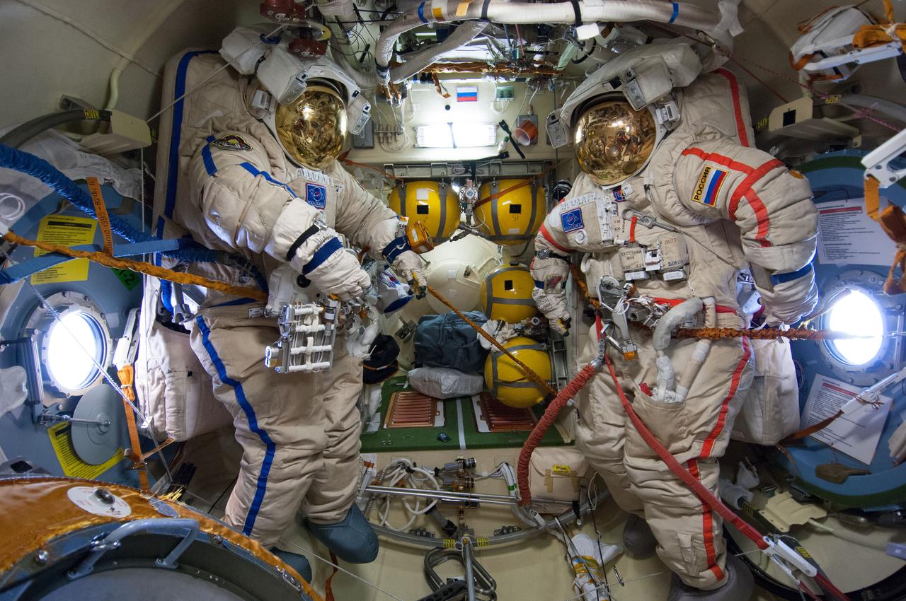 ISS040-E-095619 (17 Aug. 2014) --- Unoccupied Russian Orlan spacesuits for Russian cosmonauts Oleg Artemyev (blue stripes) and Alexander Skvortsov (red stripes), both Expedition 40 flight engineers, are pictured in the Pirs Docking Compartment of the International Space Station on the eve of the spacewalk scheduled for Aug. 18, 2014.